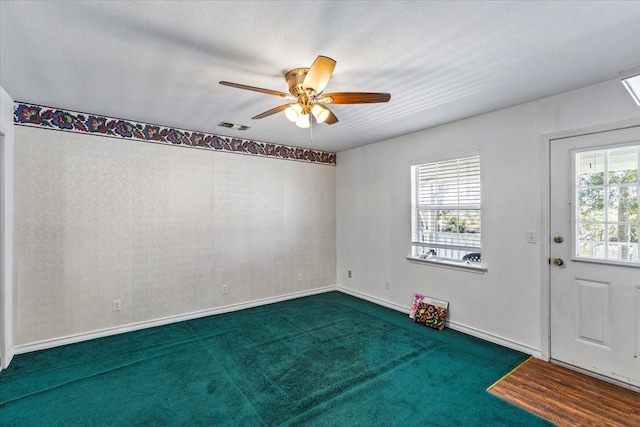 carpeted spare room with visible vents, ceiling fan, and baseboards