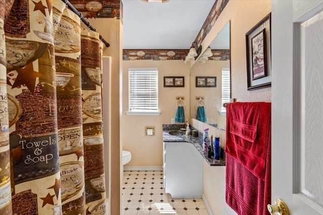 bathroom featuring curtained shower, toilet, vanity, baseboards, and tile patterned floors