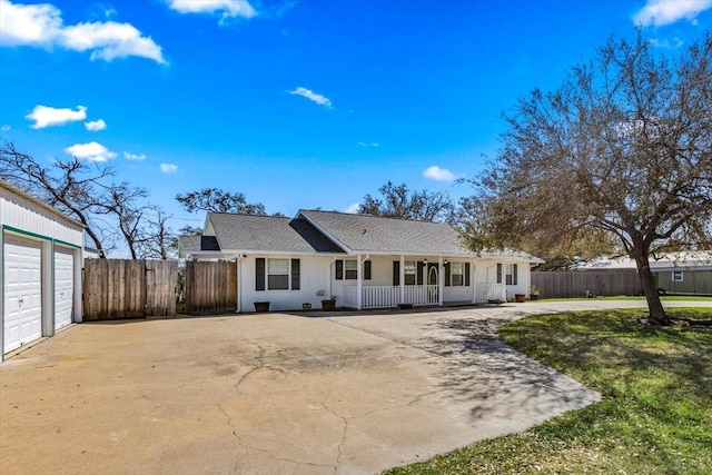 rear view of property featuring driveway, fence, and covered porch