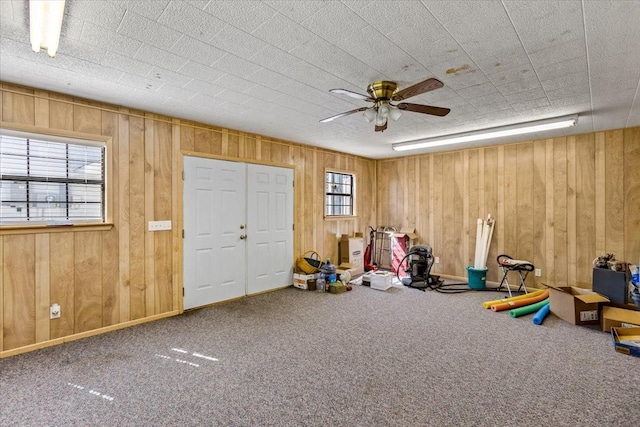 rec room with carpet floors, wood walls, and ceiling fan