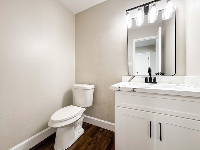 bathroom featuring vanity, wood finished floors, toilet, and baseboards