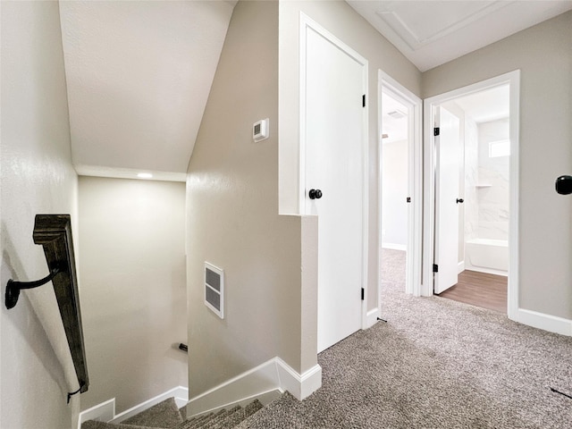 hall featuring carpet flooring, visible vents, and baseboards