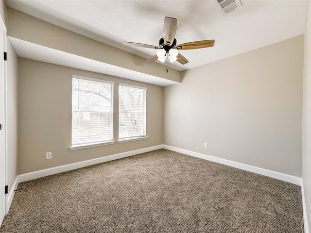 carpeted empty room with ceiling fan, visible vents, and baseboards