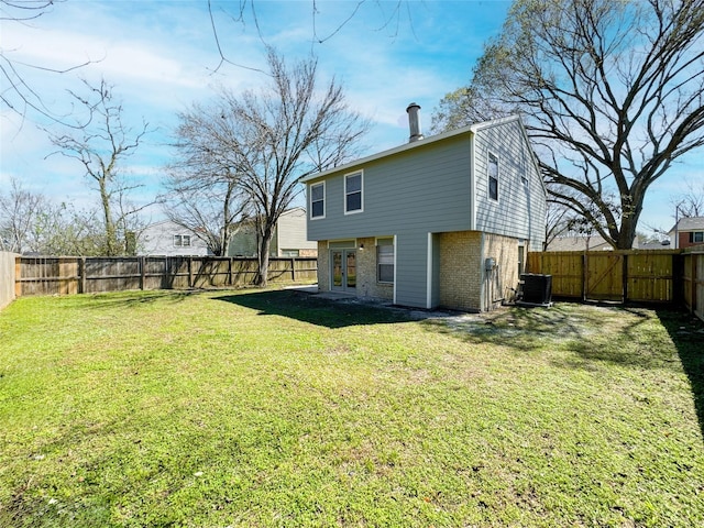 view of yard with french doors, a fenced backyard, and central AC unit