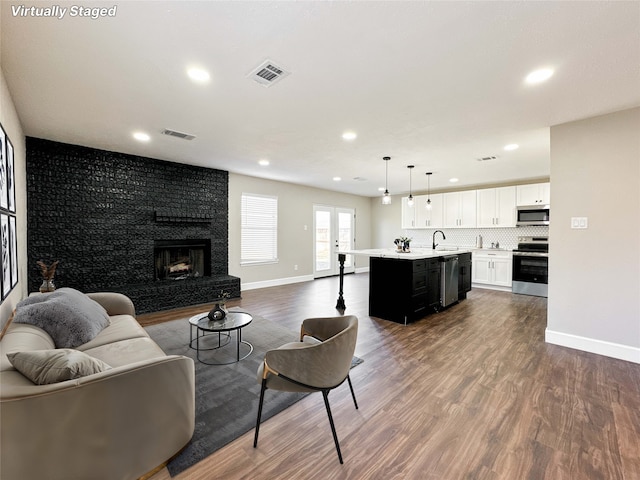 living room featuring dark wood-style floors, baseboards, a fireplace, and visible vents