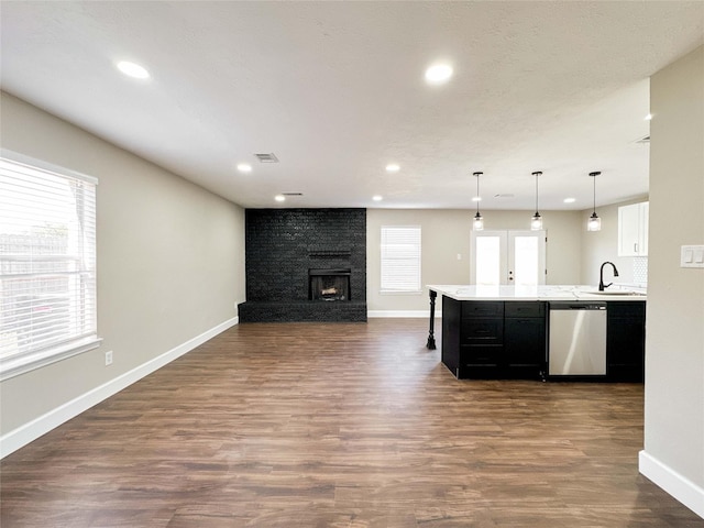 kitchen with visible vents, open floor plan, light countertops, dark cabinetry, and stainless steel dishwasher