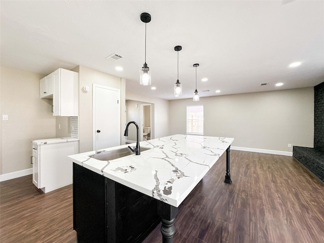 kitchen featuring baseboards, dark wood-type flooring, light stone countertops, white cabinetry, and a sink