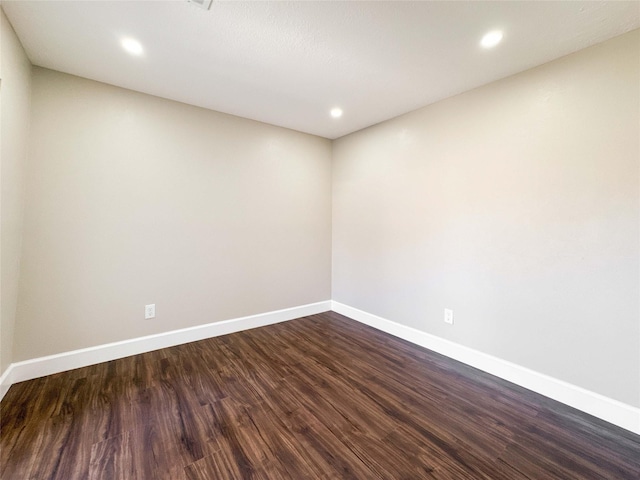 spare room featuring dark wood-style flooring, recessed lighting, and baseboards