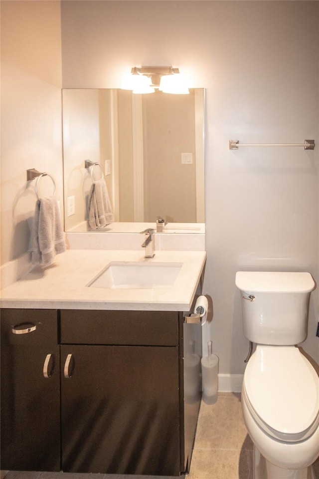 half bath featuring vanity, tile patterned floors, toilet, and baseboards