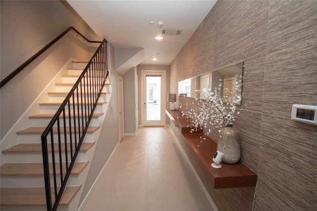 foyer featuring visible vents, baseboards, recessed lighting, stairs, and an accent wall