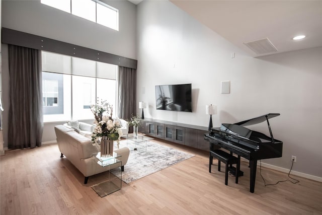 living room with visible vents, baseboards, wood finished floors, and a towering ceiling