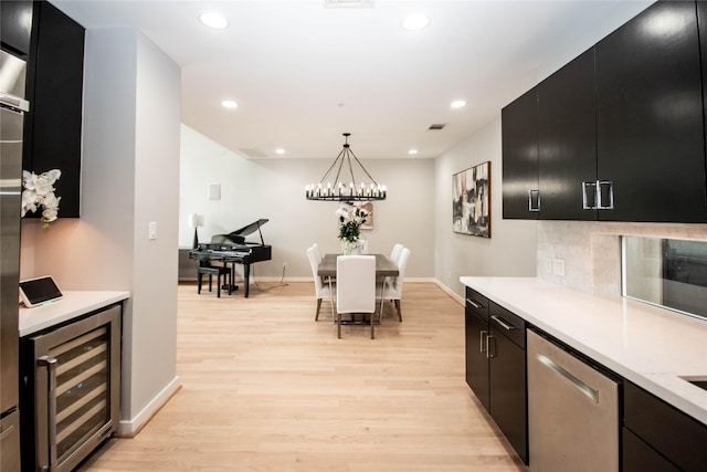 kitchen with wine cooler, dishwasher, dark cabinetry, and light countertops