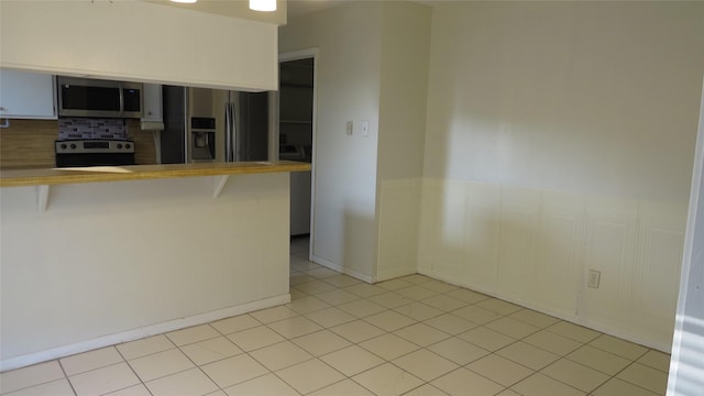 kitchen with light tile patterned floors, stainless steel appliances, and a kitchen breakfast bar