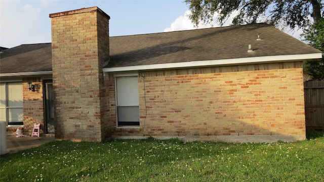 exterior space featuring brick siding, a chimney, and roof with shingles