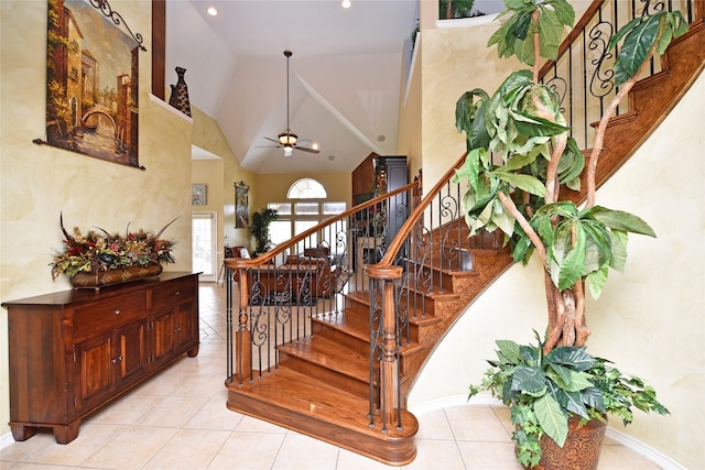 stairs with tile patterned flooring, high vaulted ceiling, and a ceiling fan