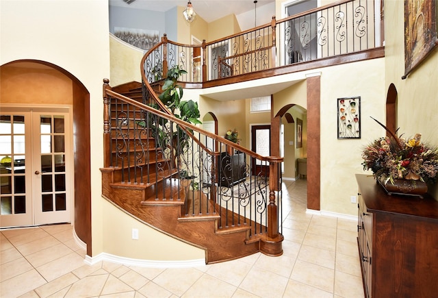 stairs featuring arched walkways, tile patterned flooring, a high ceiling, and baseboards