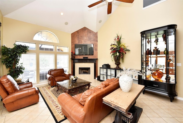 living room with high vaulted ceiling, light tile patterned flooring, baseboards, ceiling fan, and a tile fireplace