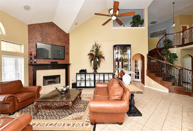 living room with visible vents, stairway, a fireplace, arched walkways, and high vaulted ceiling