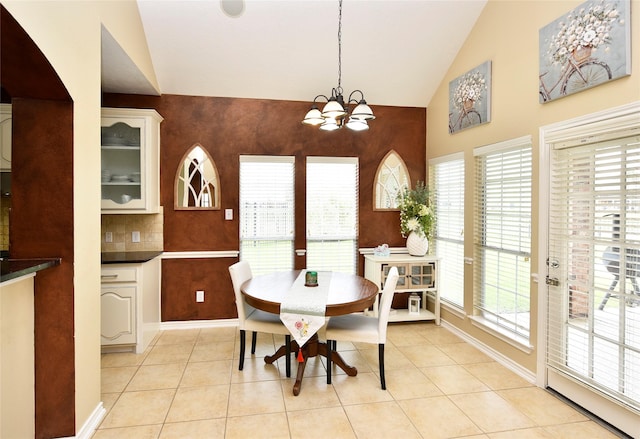 dining room with light tile patterned floors, baseboards, a notable chandelier, and high vaulted ceiling