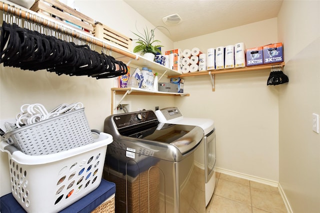 washroom featuring light tile patterned floors, baseboards, laundry area, a textured ceiling, and independent washer and dryer