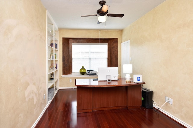 unfurnished office with built in features, baseboards, dark wood finished floors, and ceiling fan