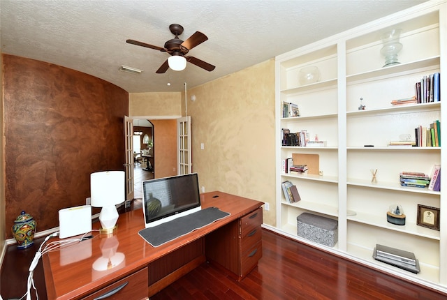 office area featuring visible vents, built in shelves, a textured ceiling, dark wood-style floors, and ceiling fan