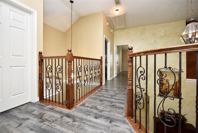 corridor featuring wood finished floors, visible vents, attic access, lofted ceiling, and an upstairs landing