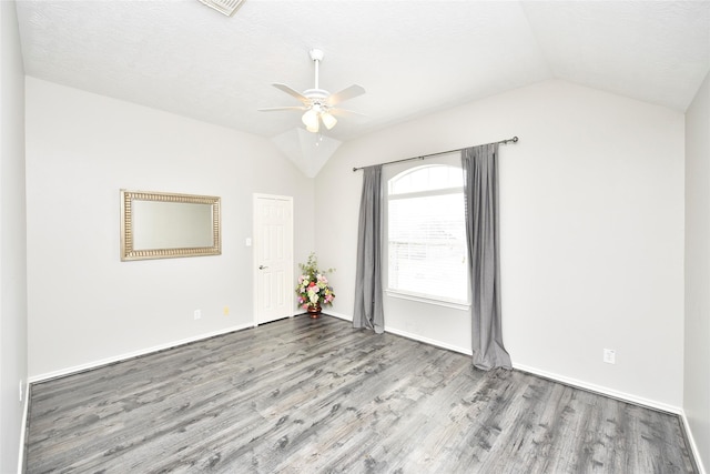 spare room featuring vaulted ceiling, wood finished floors, baseboards, and ceiling fan