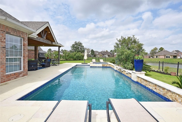 view of pool with fence, a pool with connected hot tub, and a patio area