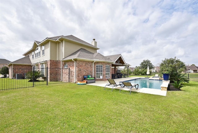 rear view of property featuring a patio, a chimney, central air condition unit, a lawn, and brick siding