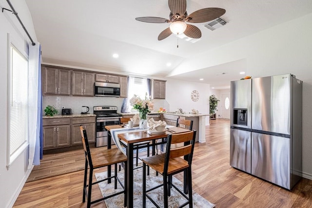 dining space featuring lofted ceiling, light wood-style flooring, recessed lighting, visible vents, and baseboards