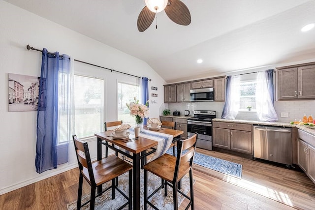 dining room featuring light wood-type flooring, lofted ceiling, plenty of natural light, and recessed lighting