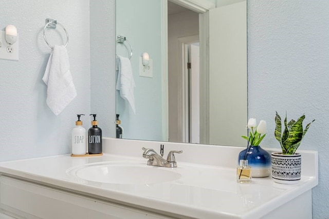 bathroom with a textured wall and vanity