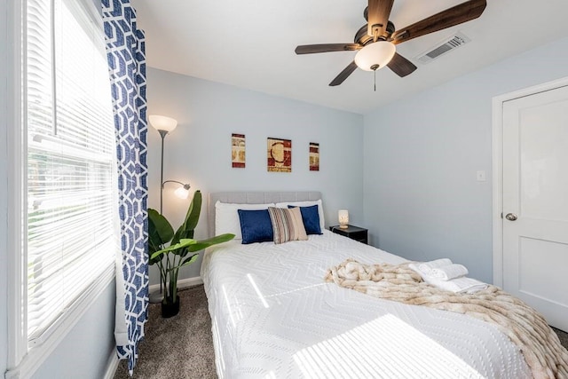 bedroom with ceiling fan, multiple windows, visible vents, and carpet flooring