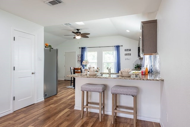 kitchen featuring a peninsula, visible vents, wood finished floors, and freestanding refrigerator