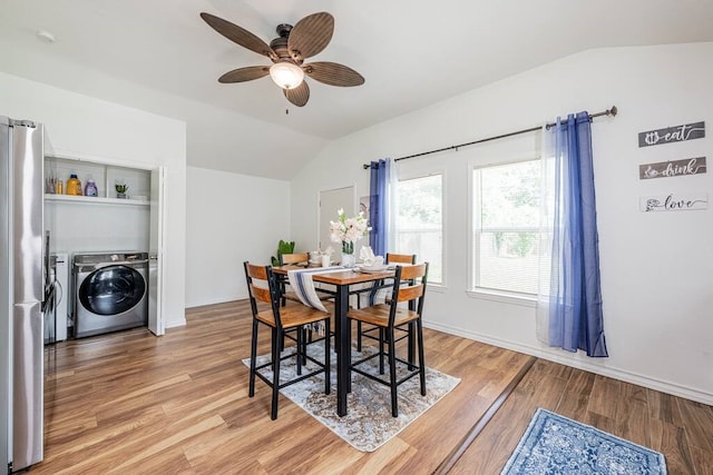 dining area featuring light wood-style floors, washing machine and dryer, vaulted ceiling, and baseboards