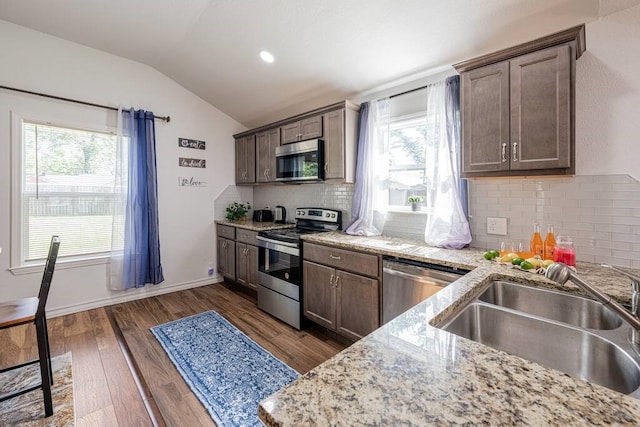 kitchen with tasteful backsplash, dark wood-style flooring, vaulted ceiling, stainless steel appliances, and a sink