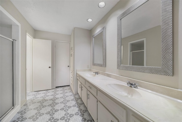 full bath with double vanity, a stall shower, a sink, and recessed lighting