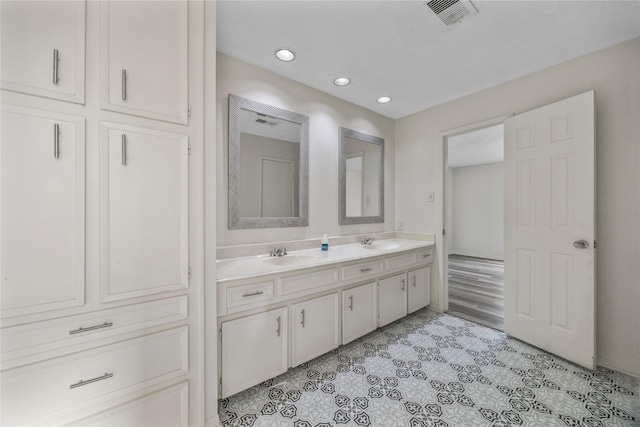 bathroom with double vanity, a sink, visible vents, and tile patterned floors