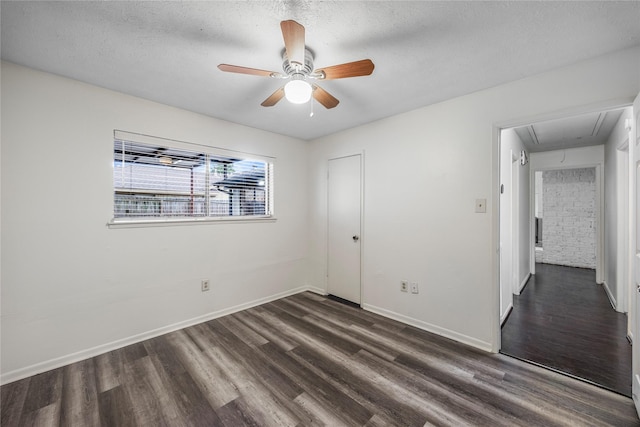 spare room with attic access, baseboards, and dark wood finished floors