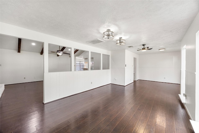 spare room with visible vents, dark wood finished floors, a ceiling fan, and beamed ceiling