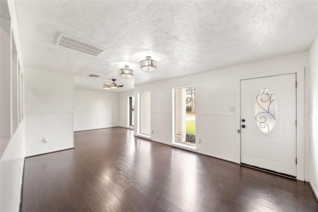 foyer entrance with visible vents, dark wood finished floors, and a textured ceiling