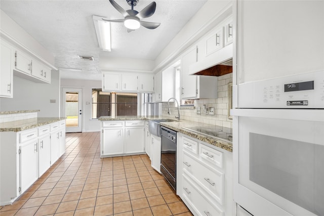 kitchen with light tile patterned floors, visible vents, backsplash, black appliances, and a sink