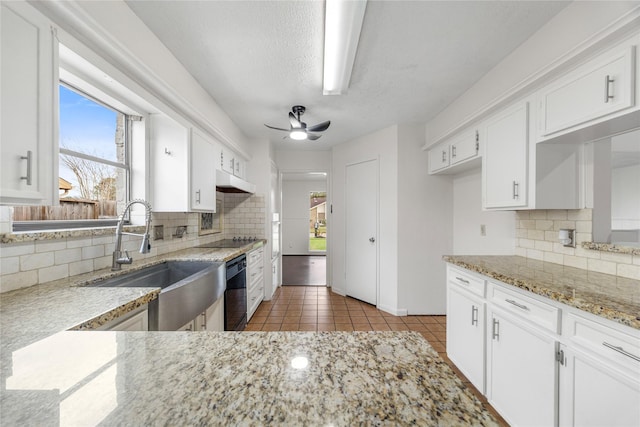 kitchen featuring ceiling fan, light tile patterned floors, light stone counters, a sink, and white cabinetry