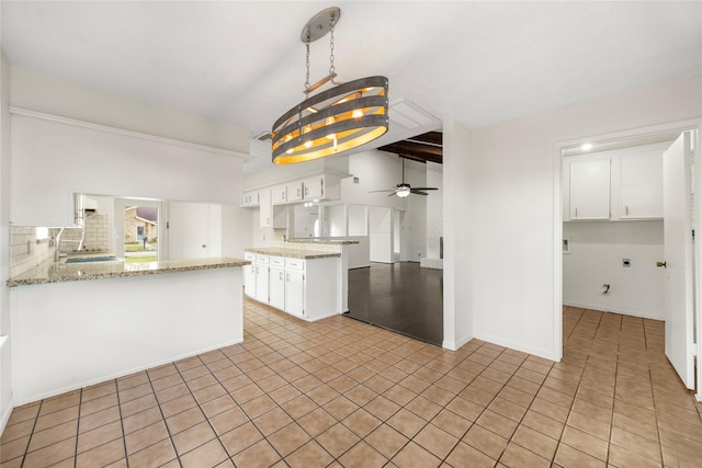 kitchen featuring light stone counters, white cabinetry, a peninsula, and decorative backsplash