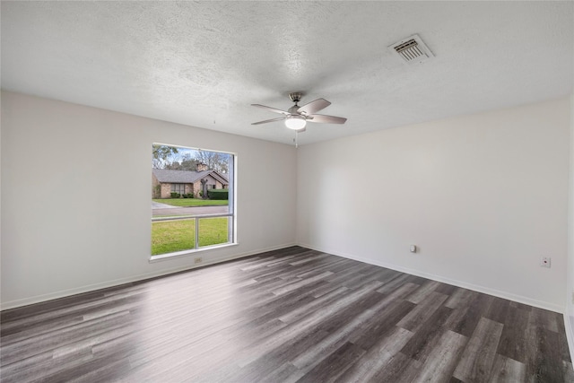 spare room with a textured ceiling, dark wood finished floors, visible vents, and baseboards