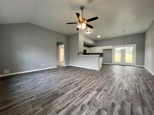 unfurnished living room featuring dark wood-type flooring, french doors, baseboards, and ceiling fan with notable chandelier