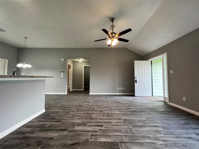 unfurnished living room featuring wood tiled floor, baseboards, vaulted ceiling, and ceiling fan with notable chandelier