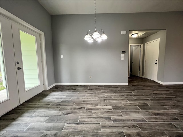 spare room with baseboards, a chandelier, and wood finish floors