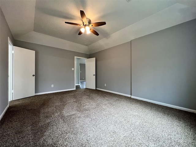 interior space featuring baseboards, dark carpet, and a ceiling fan